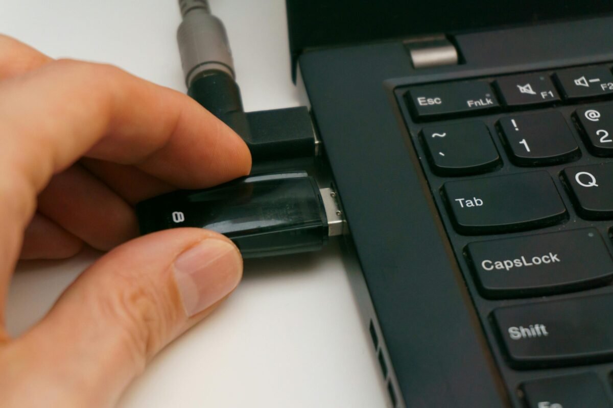 A Close Up Of A Hand Inserting A Usb Drive Into A Laptop Port, Highlighting Technology And Connectivity.